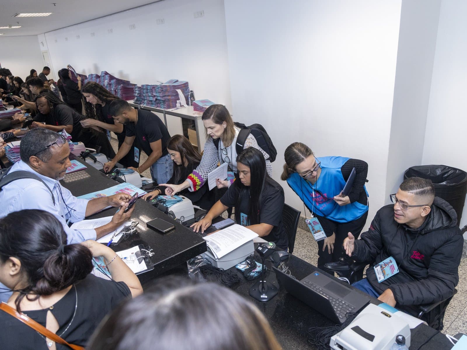 Credenciamento de um evento com a equipe atendendo os participantes nos balcões, impressoras de crachá e computadores